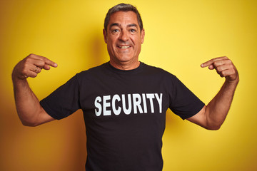 Middle age safeguard man wearing security uniform over isolated yellow background very happy pointing with hand and finger