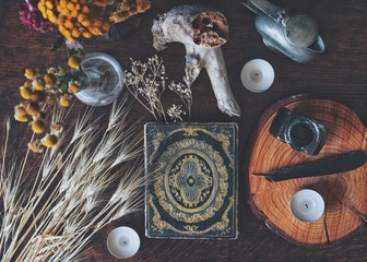 Flat lay of witch's altar space with a grimoire (vintage book from 1837) and other various items -...