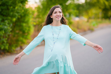 Happy young pregnant girl. on a green background. in a comfortable dress. Portrait of a happy and cheerful pregnant woman