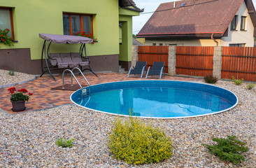 small home swimming pool with two black sun loungers and rocking bench