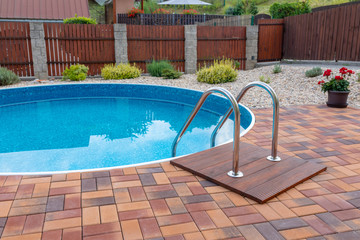 small home swimming pool with two black sun loungers