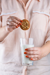 A glass of fresh milk and fragrant cookies in female hands with a beautiful manicure.