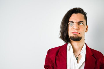 Young man with a coin in his eye and makes a strange face.