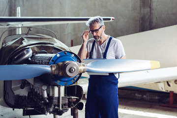 Aircraft maintenance mechanic inspects  plane engine