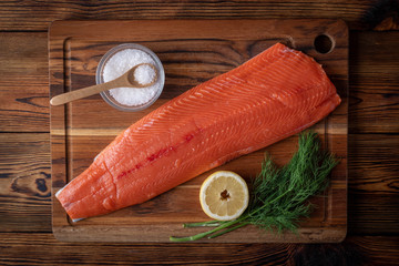 whole raw salmon fillet on wooden cutting board