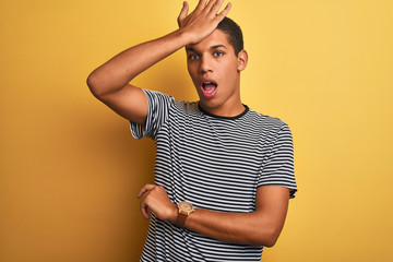 Young handsome arab man wearing navy striped t-shirt over isolated yellow background surprised with...