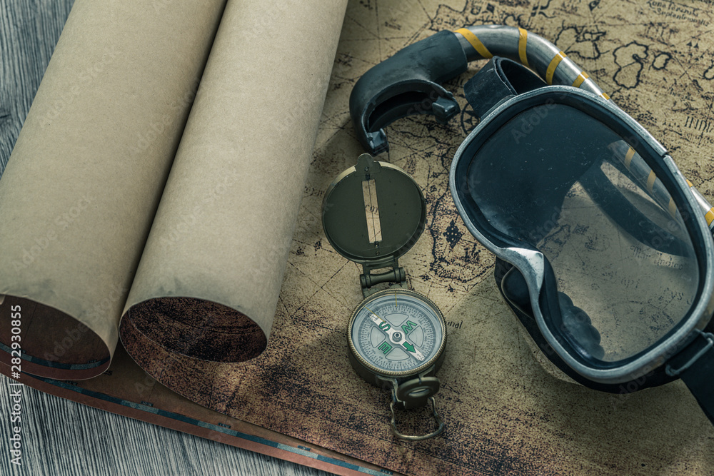 Poster old map with a compass, notebook and diving equipment. the concept of searching for interesting divi