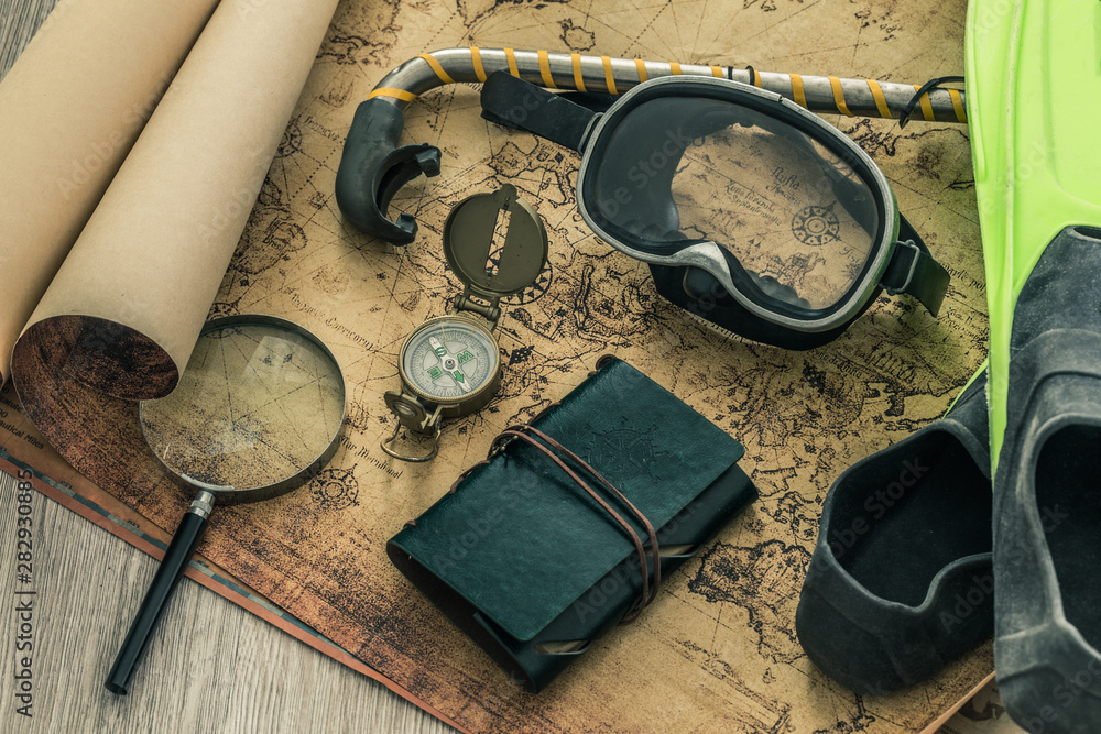 Poster old map with a compass, notebook and diving equipment. the concept of searching for interesting divi