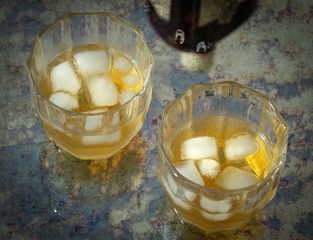 two glasses of whiskey with ice on a stylish counter