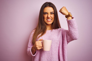 Young beautiful woman drinking cup of coffee standing over isolated pink background annoyed and...