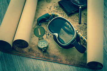 old map with a compass, notebook and diving equipment.  The concept of searching for interesting...