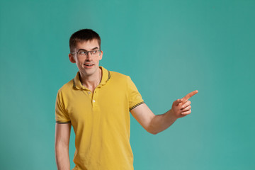 Fototapeta premium Handsome guy in a yellow casual t-shirt is posing over a blue background.