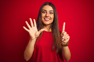 Young beautiful woman wearing t-shirt standing over isolated red background showing and pointing up with fingers number six while smiling confident and happy.