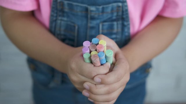 Hands of a child with colored crayons closeup. Little girl's hands with an armful of crayons.