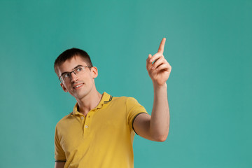 Fototapeta premium Handsome guy in a yellow casual t-shirt is posing over a blue background.