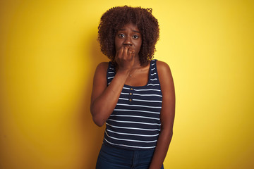 Young african afro woman wearing striped t-shirt over isolated yellow background looking stressed...