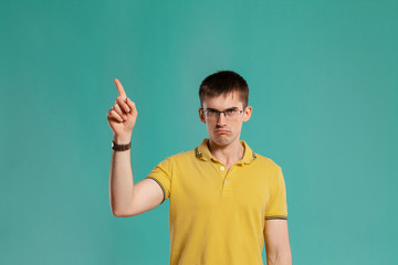 Fototapeta premium Handsome guy in a yellow casual t-shirt is posing over a blue background.