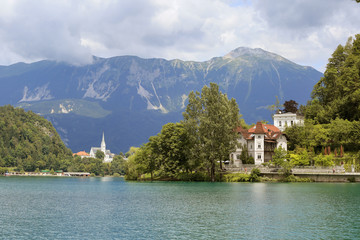 Fototapeta na wymiar Lake Bled Slovenia. Beautiful mountain lake in summer with small Church on an island with castle on cliff and european alps in the background.