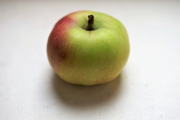small green red apple on the white table
