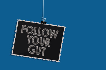 Writing note showing Follow Your Gut. Business photo showcasing Listen to intuition feelings emotions conscious perception Hanging blackboard message communication information blue background