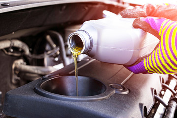 Change the Oil. Hand mechanic in repairing car. Close up oil for car engine. Motor oil pouring to car engine. Refuelling and pouring oil into the engine motor. Maintenance. Car detailing