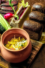Sauerkraut in a wooden barrel and cabbage soup in the background
