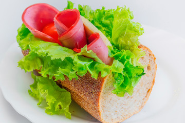 Long sandwich with ham, cheese, tomatoes, red onion and lettuce. Isolated on white. Another angle available