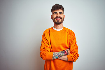 Young man with tattoo wearing orange sweater standing over isolated white background happy face...