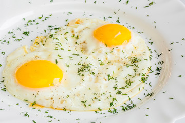 Close-up fried egg in a plate with salt and pepper and herbs. two eggs