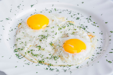 Close-up fried egg in a plate with salt and pepper and herbs.
