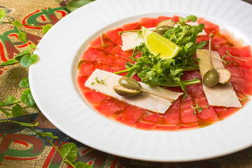 Marbled beef carpaccio with arugula, lemon and parmesan cheese. Top view, flat lay with copy space Side view