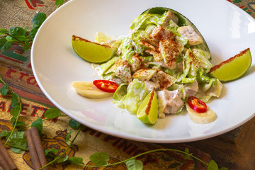 White Restaurant Plate of Caesar Salad with Chicken, Homemade Anchovies Sauces, Croutons, Tomatoes, Greens. Beautiful Delicacy Cesar Salat on Natural Dark Stone and Leaves Side view
