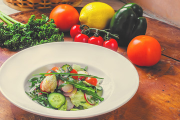 large plate with various kinds of tropical fruit flowers. Food for vegetarians, vegans and raw foodists. On a white plate - salad, arugula, apple, cucumber, radish, onion, tomato. Side view