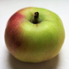 one green with red apple on the white table