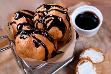 Topping profiterole tower with melted dark chocolate close-up.