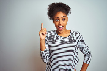 African american woman wearing navy striped t-shirt standing over isolated white background...