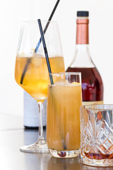 Group of different glasses with cocktails and a bottle of cognac on a background on a white background