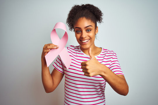 Young african american woman holding cancer ribbon over isolated white background happy with big smile doing ok sign, thumb up with fingers, excellent sign
