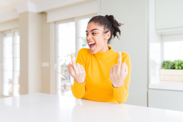 Beautiful african american woman with afro hair wearing a casual yellow sweater Showing middle...