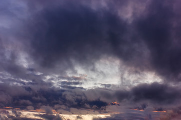 Dark rain clouds during sunset. Dramatic sky during sunset. Dark storm clouds with black and white highlights.