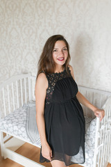 Pregnant in a white room. Attractive pregnant woman holds her belly. The last months of pregnancy.