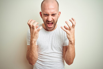 Young bald man with beard wearing casual white t-shirt over isolated background celebrating mad and...