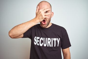 Young safeguard man wearing security uniform over isolated background peeking in shock covering...