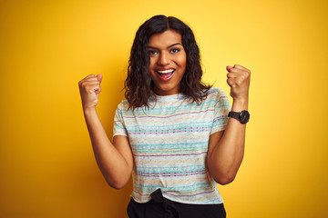 Beautiful transsexual transgender woman wearing t-shirt over isolated yellow background celebrating surprised and amazed for success with arms raised and open eyes. Winner concept.