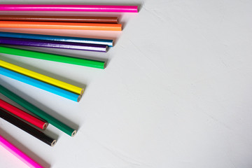 Obraz premium Many colored pencils lie on a white background. Copy spase. The concept of back to school, the educational process, study at school, drawing