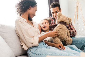 african american mother holding teddy bear while kid looking at mom
