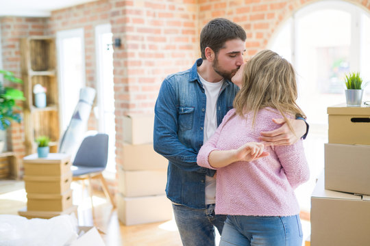 Young couple dancing celebrating moving to new apartment around cardboard boxes