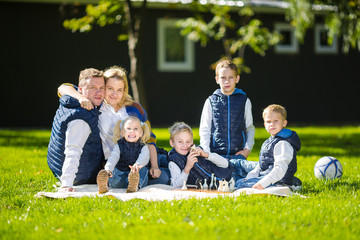 Fototapeta premium Big Family Relaxing In Green Nature. Happy family portrait on outdoor, group six people sit on grass, summer season, child and parent. Children, parenthood and nature concept. picnic outdoors on lawn