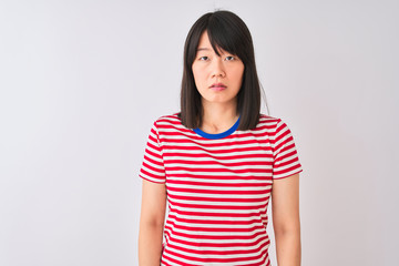 Obraz premium Young beautiful chinese woman wearing red striped t-shirt over isolated white background Relaxed with serious expression on face. Simple and natural looking at the camera.