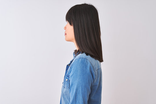 Chinese woman wearing denim shirt and red striped t-shirt over isolated white background looking to side, relax profile pose with natural face with confident smile.